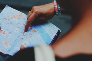 A hand with colorful bracelets pointing to a location on a city map